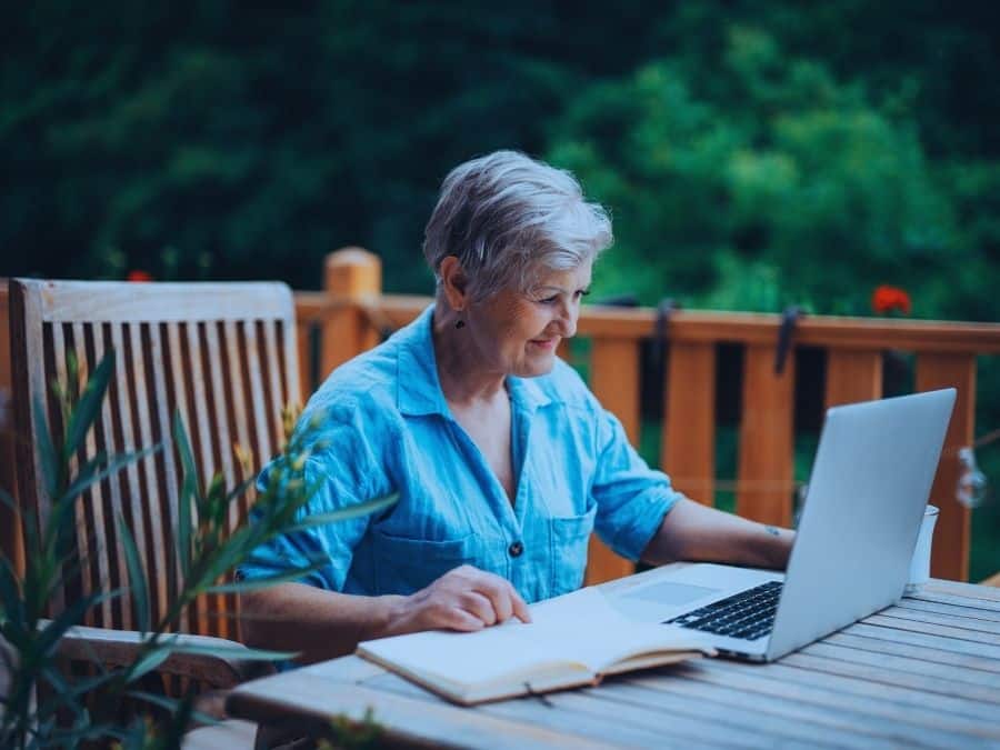 Transition to retirement strategies featured image showing a mature woman working on a laptop outside at home.