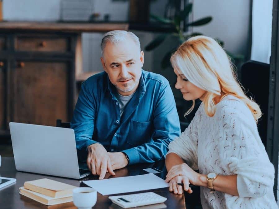 Pre-retirement couple working on a laptop at home to figure out how much super to retire on $80k